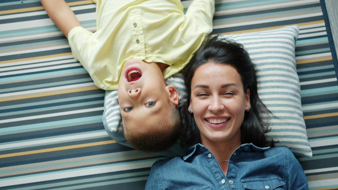 happy mom and son lying on a striped carpet