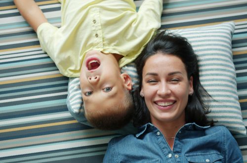 happy mom and son lying on a striped carpet